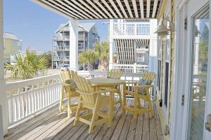 Sea BreezeにあるStay Salty Villa with views of canal and short walk to beachの木製ポーチ(テーブル、椅子付)