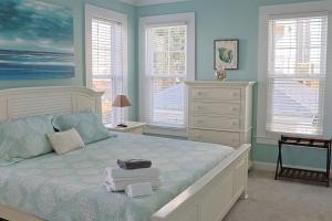 Sea BreezeにあるStay Salty Villa with views of canal and short walk to beachのベッドルーム1室(青い壁と窓のある大型ベッド1台付)