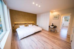 sypialnia z dużym białym łóżkiem i drewnianą podłogą w obiekcie La Cachette w mieście Hakodate