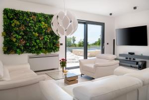 a living room with white furniture and a green wall at Villa MaEm in Juršići