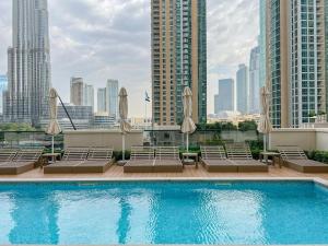 a swimming pool with chairs and umbrellas on a building at Luxury Apartment with Full Burj Khalifa and Downtown Views in Dubai
