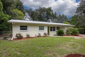 a small white house with a yard at Vibrant 4bd with Games & Backyard - 5 Mins to UF in West Hills