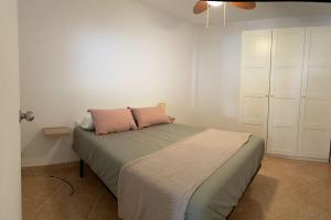 una camera da letto con un letto con due cuscini rosa sopra di Neruka House a Torremolinos