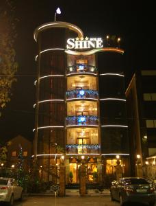 a tall building with a lit up sign on it at Shine House Hotel in Adler