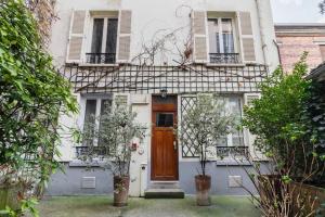 una casa bianca con porta marrone e finestre di Studio Confortable proche métro - Saint mandé a Saint-Mandé