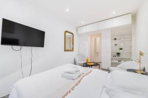 una camera bianca con letto e TV a schermo piatto di Studio Confortable proche métro - Saint mandé a Saint-Mandé