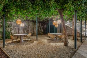a patio with two tables and chairs and a tree at Arrábida Guest House in Setúbal