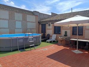 a patio with a hot tub and an umbrella at MUSEUM La Almazara de Alcabón 11th century in Alcabón