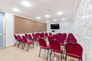 a conference room with red chairs and a screen at Hotel Parque 63 in Bogotá