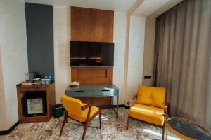 a room with a desk and two chairs and a television at Aurum Garden Hotel in Shymkent