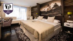 a hotel room with a large bed and a desk at Wellness Hotel Alpenhof in Zermatt