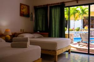 two beds in a bedroom with a view of a pool at Hotel Vista Caribe 5ta Av a 5 Pasos de la Playa in Playa del Carmen +113 photos