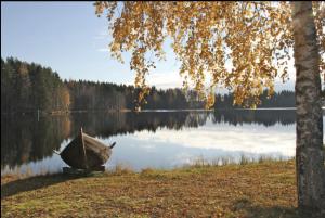 a boat sitting on the shore of a lake at TAHKOn Riihiranta - 4 bedroom villa by the lake - Tasokas tilava rantamökki in Tahkovuori
