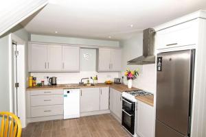 a kitchen with white cabinets and a stainless steel refrigerator at Sullcon Apartment in Killarney