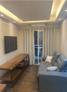 a living room with a blue couch and a flat screen tv at Apartamento Premium Taubaté in Taubaté