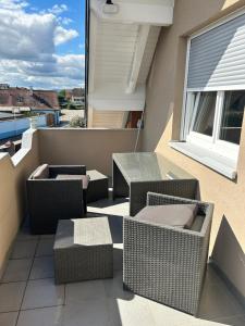a balcony with wicker chairs and tables and a window at Appartement Algo in Algolsheim