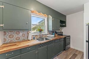 eine Küche mit grünen Schränken, einem Waschbecken und einem Fenster in der Unterkunft Riverside Retreat Waterfront, Fishing, Parks Music in Jacksonville