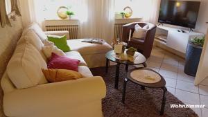 a living room with a white couch and two tables at Haus Sonnenschein in Wiltingen