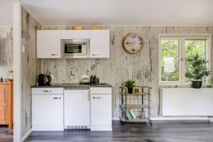 a kitchen with white cabinets and a clock on the wall at H15, Sauna- en Wellnesschalet geschikt voor 2 personen in Epe