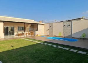 a backyard of a house with a pool and grass at Casa das Americas in Nova Almeida