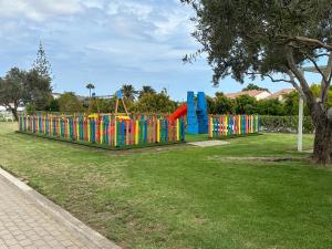 a colorful playground in a park with a tree at Blue Marlin 6 in Pasito Blanco