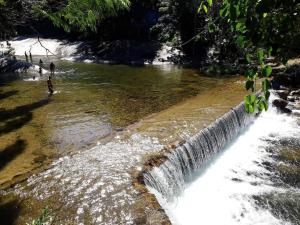a waterfall on a river with people standing in the water at Família Augusto in Paraty