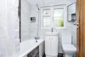 a white bathroom with a toilet and a sink at Modern 4-Bed House Corporate & Group Friendly in Stoughton +27 photos