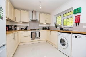 a kitchen with white cabinets and a washer and dryer at Modern 4-Bed House Corporate & Group Friendly in Stoughton