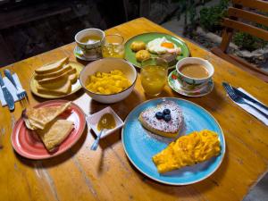 ein Holztisch mit Tellern mit Frühstücksspeisen und Getränken in der Unterkunft Vito Hotel Boutique Taganga in Taganga