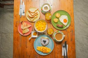 a wooden table topped with plates of breakfast foods at Vito Hotel Boutique Taganga in Taganga