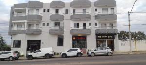 ブルマードにあるHotel terceiro milênio 1の前に車が駐車されている白い建物