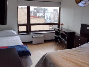 a bedroom with a bed and a desk and a window at Depto torre Bayres Obelisco in Buenos Aires