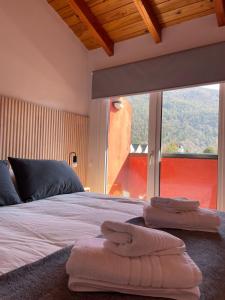 Un dormitorio con una cama con toallas. en El departamento esperado en el Sur - Edificio Loretta I, en San Martín de los Andes