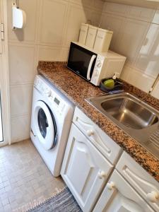 a kitchen with a washing machine and a microwave at Ribeirinho Apartment - Machico Beach in Machico