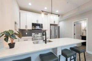 a kitchen with white cabinets and a kitchen island with stools at Modern LUX 2BR Apartment in DC with Patio in Washington