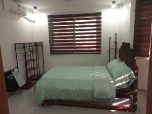 a bedroom with a bed with green sheets and a window at Dhadi Doodz Travellers Inn in San Agustin