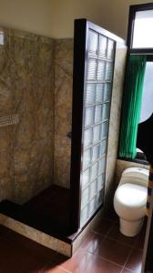 a bathroom with a toilet and a shower with a window at Ayu Taman Sari in Candidasa