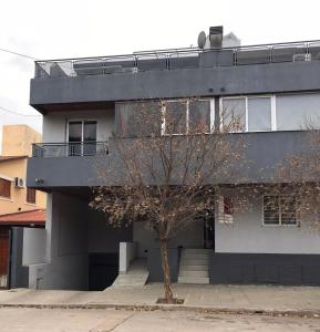 a building with a tree in front of it at Departamento céntrico Villa Carlos Paz in Villa Carlos Paz