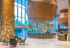 a lobby with a bar and chairs and chandeliers at Hilton Santa Marta in Santa Marta