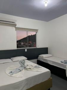 two beds in a room with a window at Residencial Flat Debora in Florianópolis +63 photos