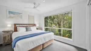 a bedroom with a bed and a large window at Mango Cottage 8, Pool, Sleeps 8, Aircon in Sawtell