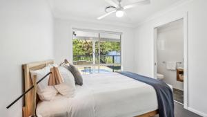 a bedroom with a large bed and a balcony at Mango Cottage 8, Pool, Sleeps 8, Aircon in Sawtell