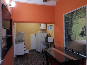 a kitchen with orange walls and a table and a refrigerator at Chalet Paloma 3 in La Falda
