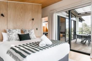 a bedroom with a large bed and a balcony at On Point House, Luxury design, Water Views in Raglan +27 photos