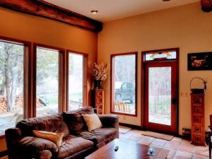 a living room with a leather couch and windows at Paradise Valley Oasis - Your Yellowstone Base Camp in Flying Y Ranch Airport