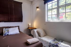 une chambre avec un lit, une chaise et des fenêtres dans l'établissement Rosehill Heights Modern 4 bedroom vacation rental, à Soufrière