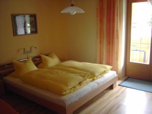 ein Schlafzimmer mit einem Bett mit gelber Bettwäsche und einem Fenster in der Unterkunft Haus Gutwenger in Sankt Jakob in Defereggen