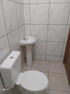 a white bathroom with a toilet and a sink at APT Raphis C in Santarém
