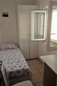 a small bedroom with a bed and a window at Apartments by the sea Korcula - 15689 in Korčula