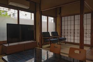 a living room with two chairs and a large screen television at CraftFlat Asakusa House in Tokyo